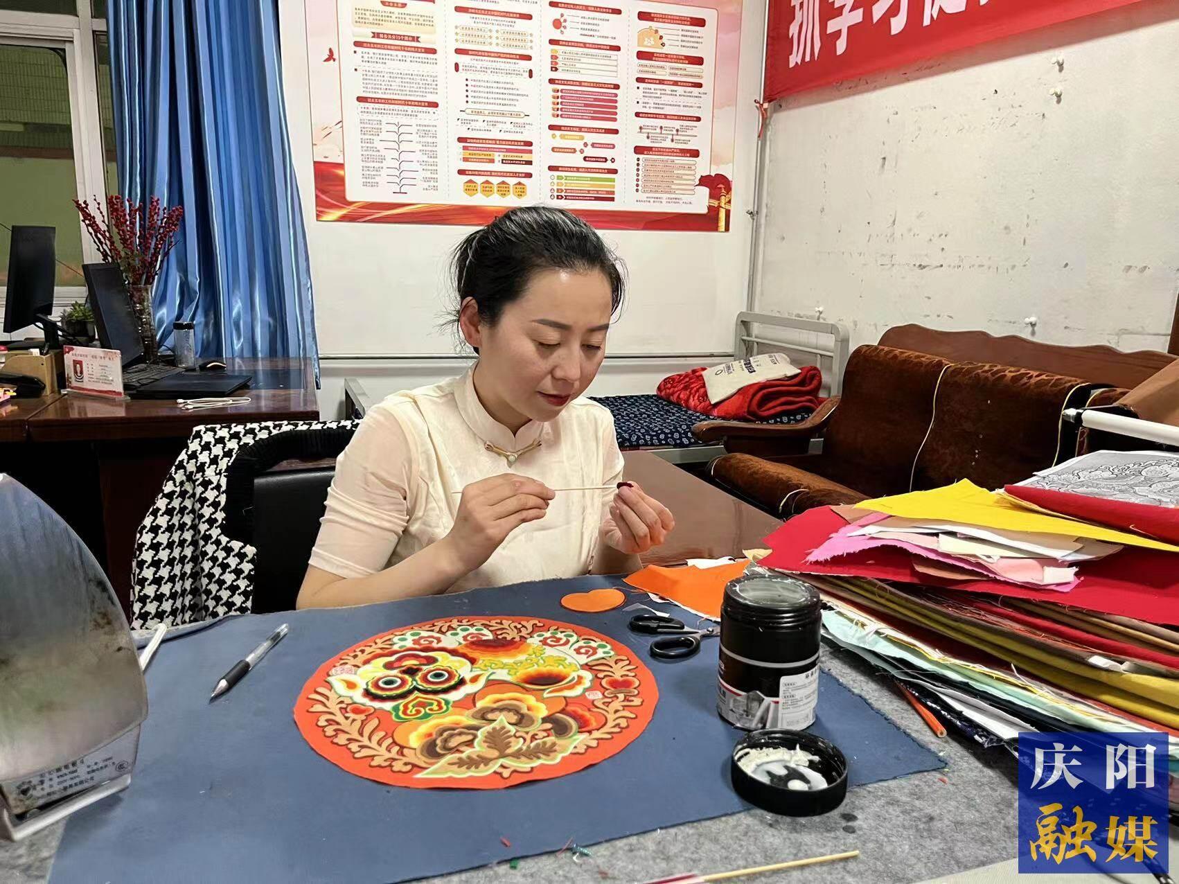 李慶英正在創(chuàng)作布貼畫(huà)作品。